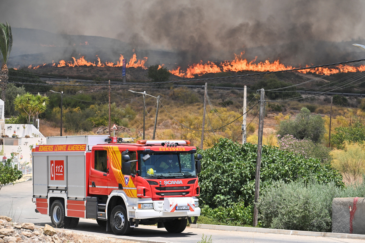 A firefighting vehicle drives by as smoke and flames rise during deadly wildfires affecting Almeria province, in Alfaix, Spain, July 10, 2026. REUTERS/Stringer