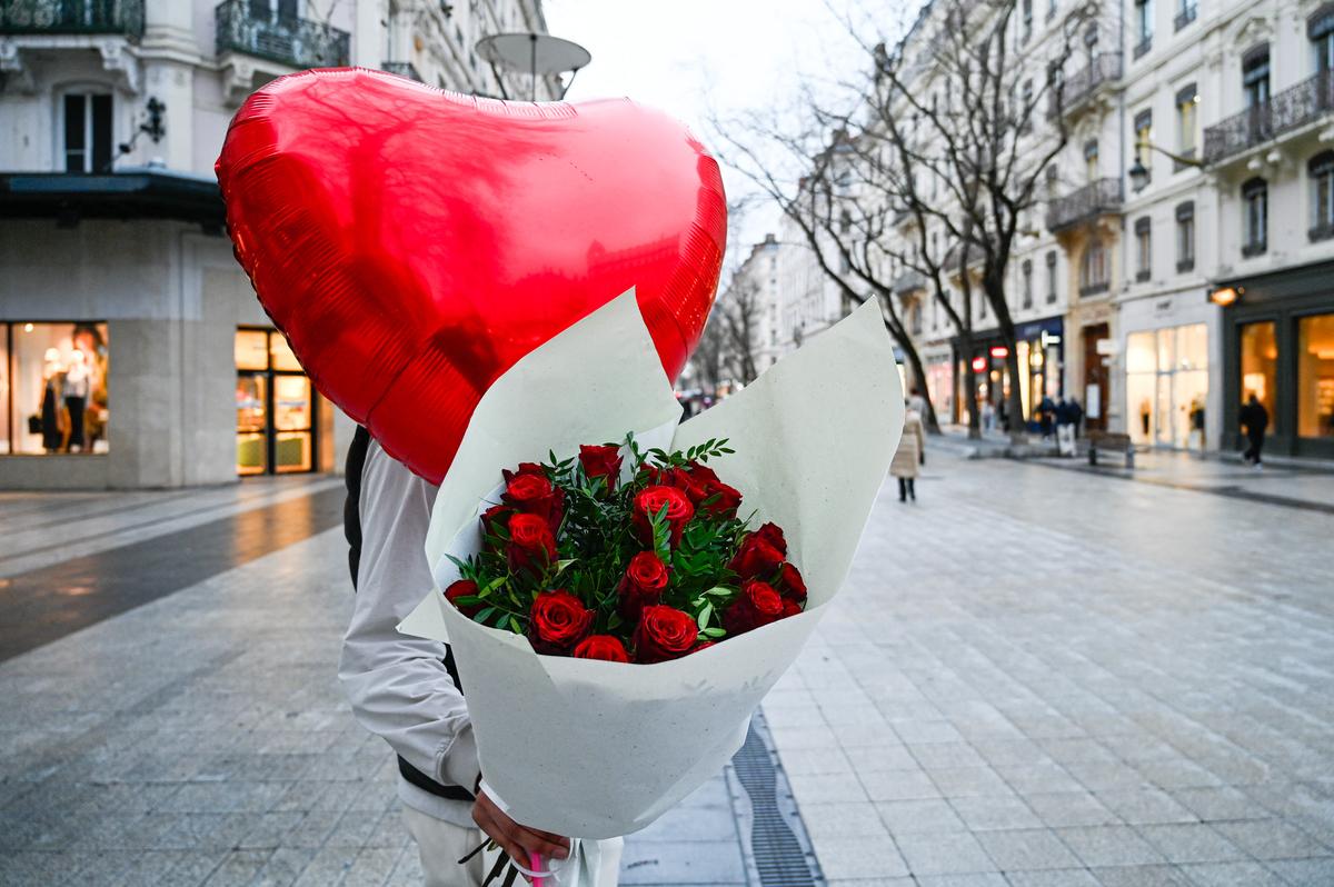 A man holds a bouquet of red roses and a red heart-shaped balloon as a Valentines’ Day gift in Lyon in France on Feb. 13 2025. 