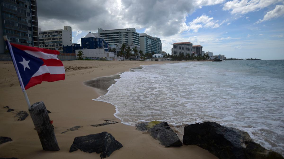 In this May 21, 2020 file photo, a Puerto Rican flag flies on an empty beach at Ocean Park, in San Juan, Puerto Rico.