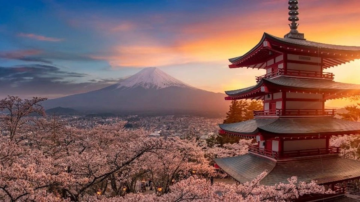 Mt. Fuji, Japan is seen in the distance with Arakura Sengen Shrine and cherry blossoms in the foreground.