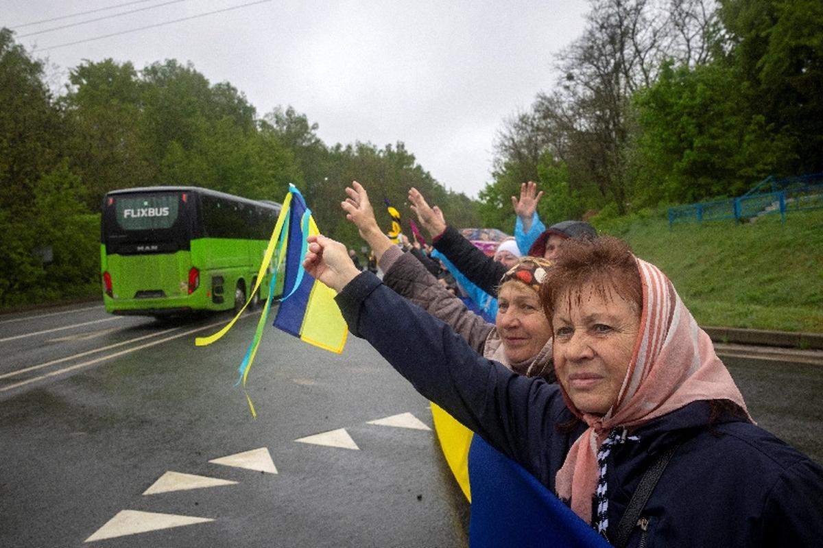 Locals greet Ukrainian servicemen and former prisoners of war (POW) as they drive past in busses after a POW swap with Russia, amid Russia's attack on Ukraine, at an undisclosed location in Ukraine May 15, 2026. REUTERS/Thomas Peter