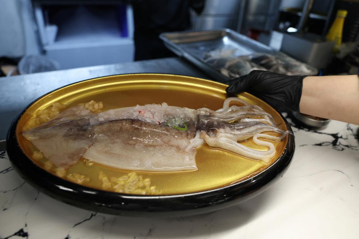 An employee serves an Argentine squid on a plate at a restaurant in Beijing, China, March 27, 2026. REUTERS/Tingshu Wang