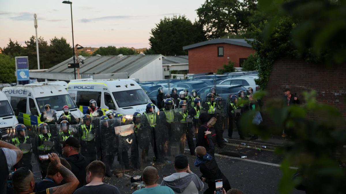 Police officers stand guard as a protester throws a brick toward them during a demonstration following the conviction of Vikrum Digwa for the murder of student Henry Nowak, in Southampton, Britain, June 2, 2026. REUTERS/Isabel Infantes