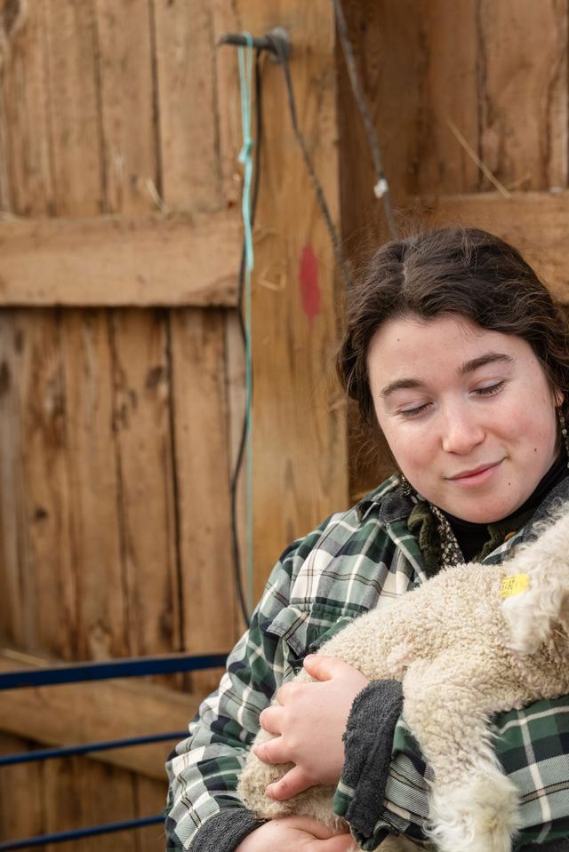  LillyAnne Keeley holds a newborn lamb in the barn at Sterling College in Craftsbury Common, Vermont, which focuses on agriculture and related disciplines. The college has announced that it will close at the end of this semester. Credit: Oliver Parini for The Hechinger Report