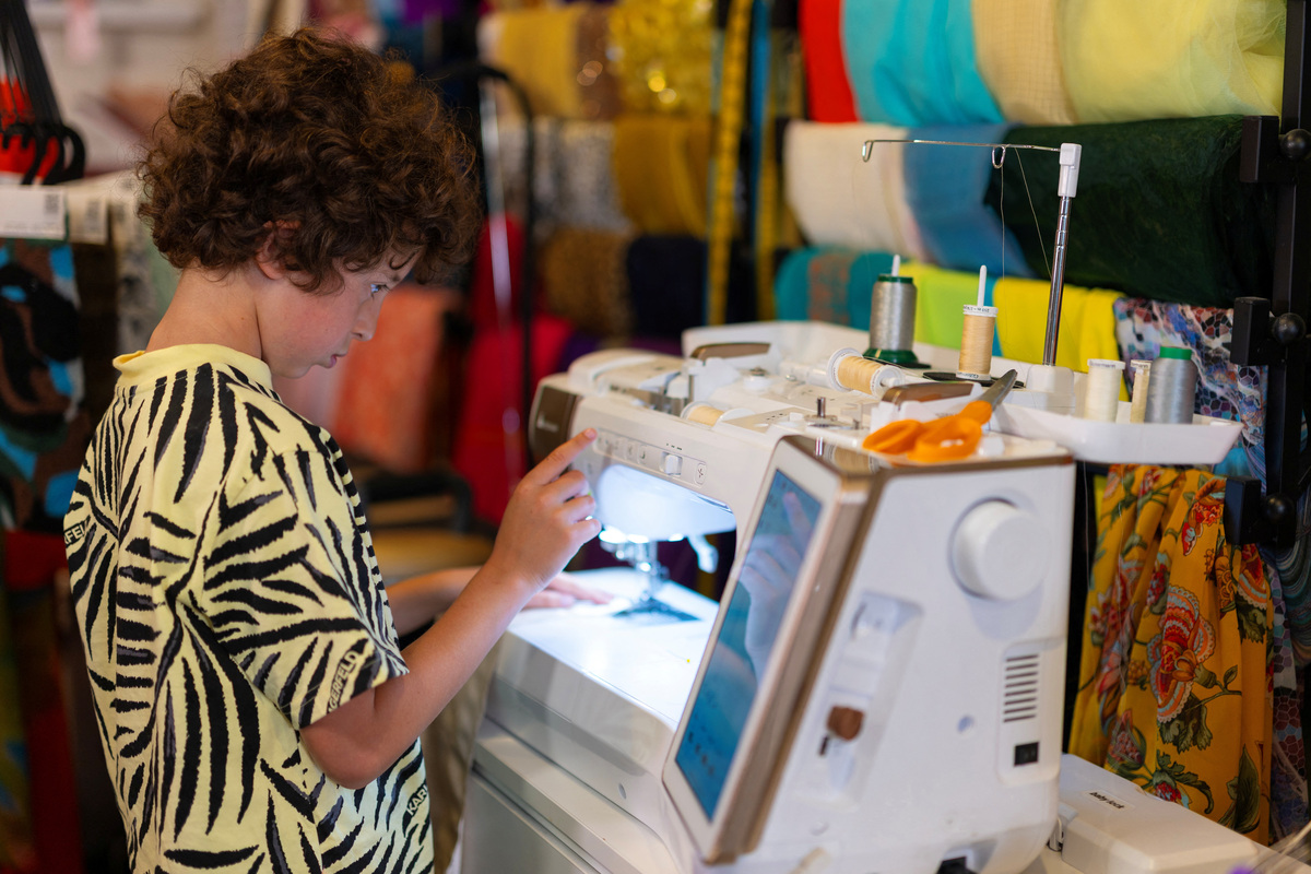 Max Alexander, 10, a fashion designer who recently debuted his first runway show in Paris, works at his sewing machine in his studio at his parents' home in Los Angeles, California, U.S., June 5, 2026. REUTERS/Mike Blake