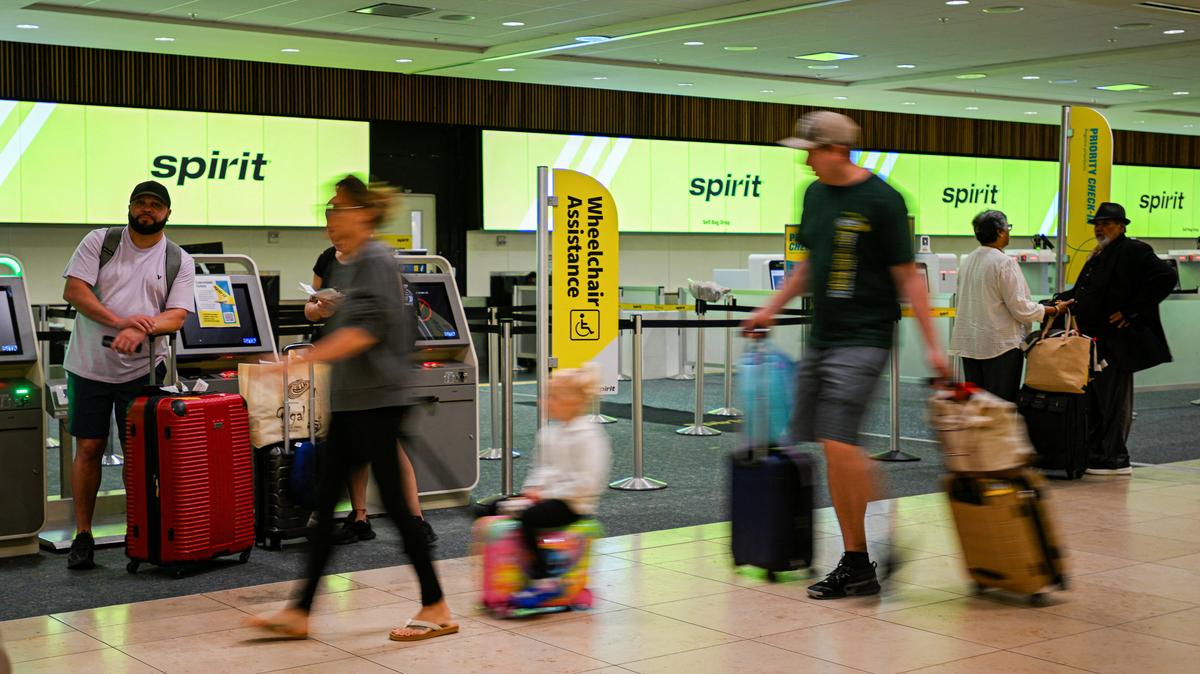 Passengers walk past the Spirit Airlines counters at Orlando (Florida) International Airport on Saturday. The carrier said on Sunday that it had almost completed refunding passengers and returning its crew to their home bases following its decision to cease operations over the weekend.