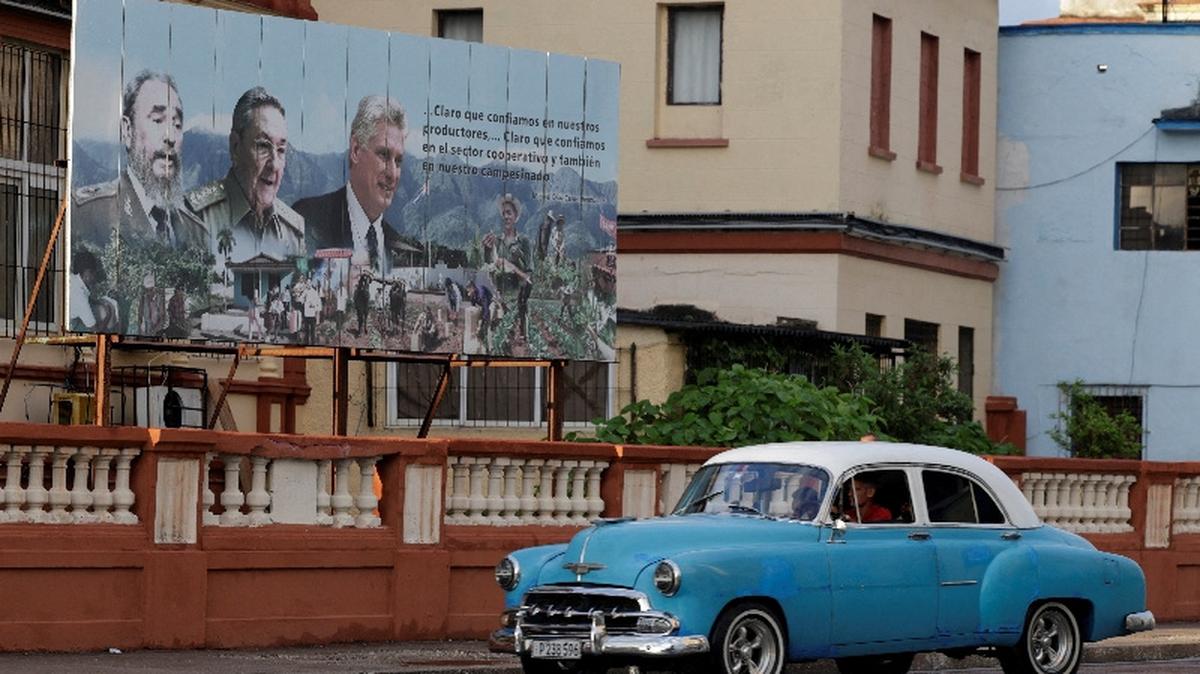 A vintage car passes by images of late Cuban President Fidel Castro, Cuba's former President Raul Castro and Cuba's President Miguel Diaz-Canel displayed on a billboard in Havana, Cuba, May 15, 2026. REUTERS/Norlys Perez