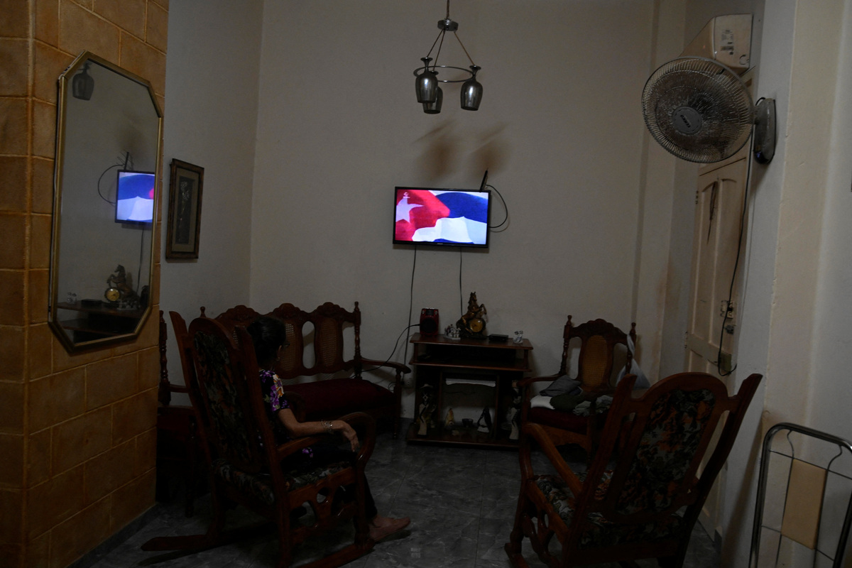 Regla Rodriguez, 70, a widow who lives off her work as a seamstress, watches a television showing a waving Cuban flag before a local newscast begins in Havana, Cuba, March 12, 2026. REUTERS/Norlys Perez