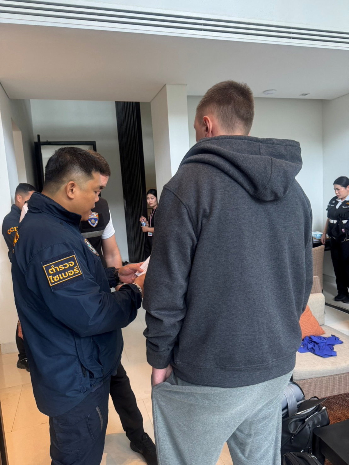 Denis Obrezko stands with police officers in Phuket, Thailand, November 12, 2025. U.S. prosecutors say Denis Obrezko previously worked for Russia's FSB intelligence agency.   Thailand's Cyber Crime Investigation Bureau/Handout via REUTERS