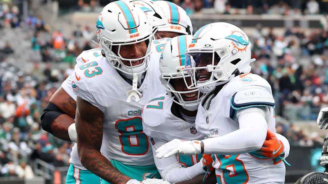 Miami Dolphins running back De'Von Achane (28) celebrates with tight end Darren Waller (83) and wide receiver Jaylen Waddle (17) after scoring a touchdown against the New York Jets during the first half at MetLife Stadium. 