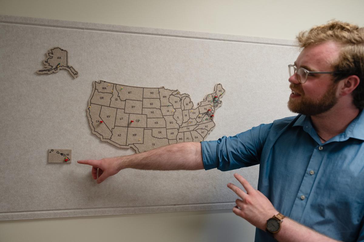  Nathan Grove, assistant dean of admissions and coordinator of rural outreach, points to a map showing the hometowns of rural students who have come to Amherst College since the college joined a coalition of selective institutions to recruit them. Credit: Lucy Lu for The Hechinger Report