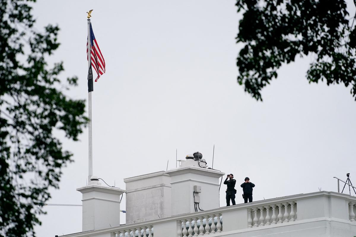 U.S. Secret Service agents keep watch on the roof of the White House after a shooting incident nearby in Washington, D.C., U.S., May 23, 2026. REUTERS/Nathan Howard