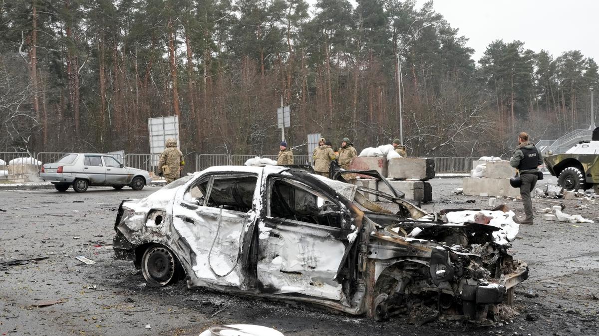 Soldados y voluntarios de las Fuerzas de Defensa Territorial de Ucrania, junto a un auto calcinado cerca de un puesto de control en Brovary, a las afueras de Kiev, Ucrania, el 1 de marzo de 2022. (AP Foto/Efrem Lukatsky)