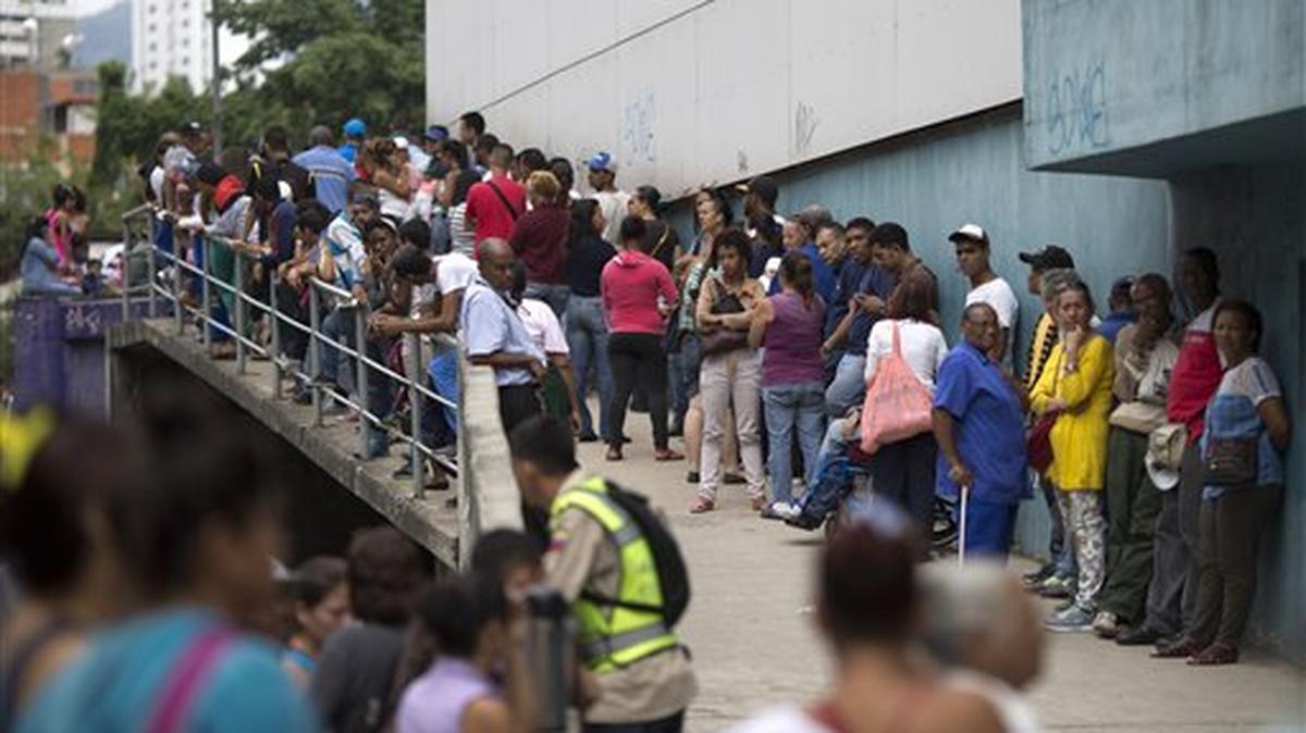 En esta imagen, tomada el 18 de noviembre de 2016, un grupo de personas espera en el exterior de un supermercado para comprar comida subvencionada por el gobierno en Caracas, Venezuela. A medida que la producción nacional se frena, el estado adquiere el rol de importar casi toda la comida que llega al país.